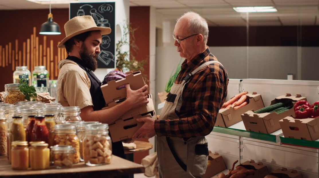Épicier devant son ordinateur créant sa vitrine en ligne